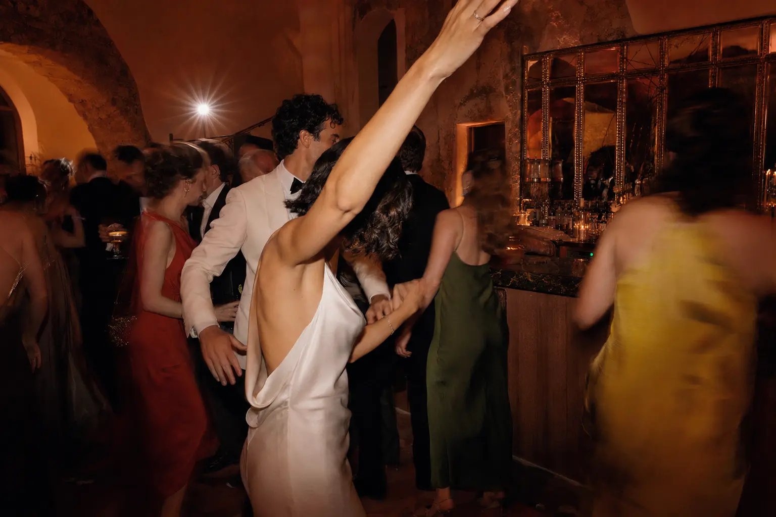 A newlywed couple dancing with their guests at a candlelit reception